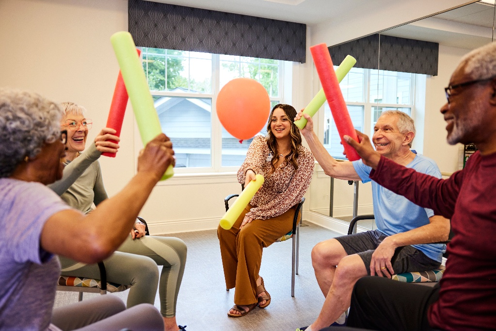 Senior living activities assistant sitting with a group of seniors playing a game