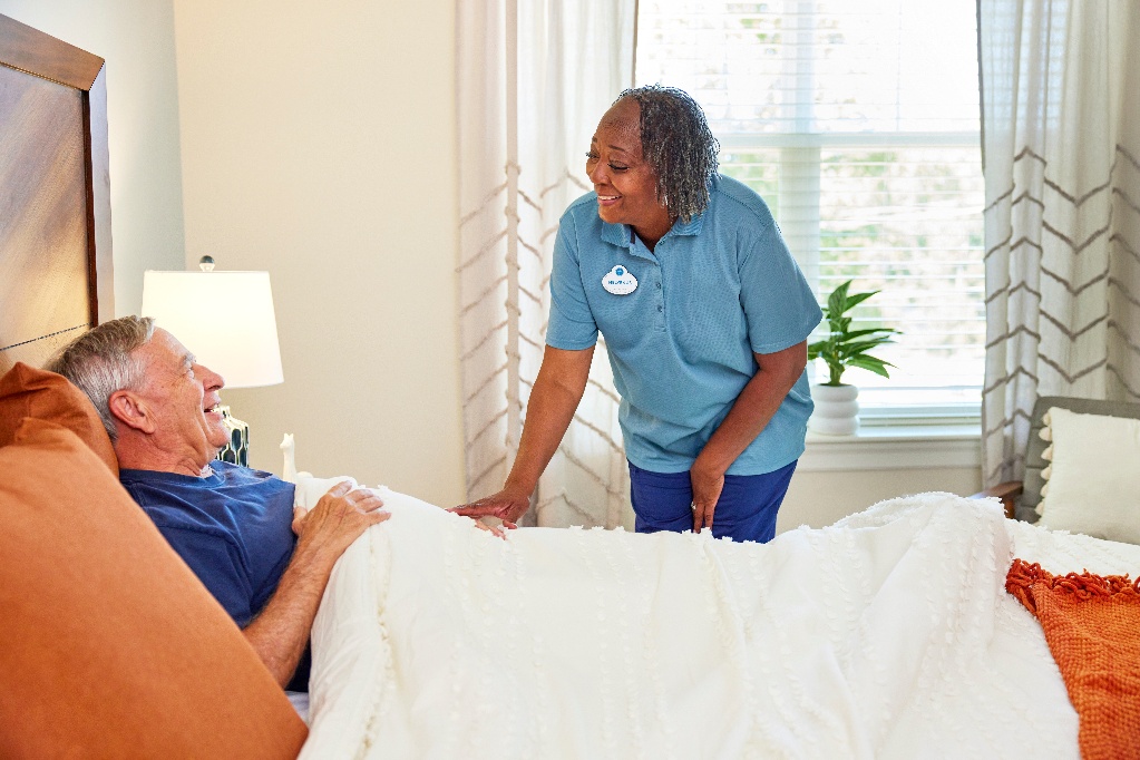 Arbor caregiver assisting a senior resident in his bed in his apartment