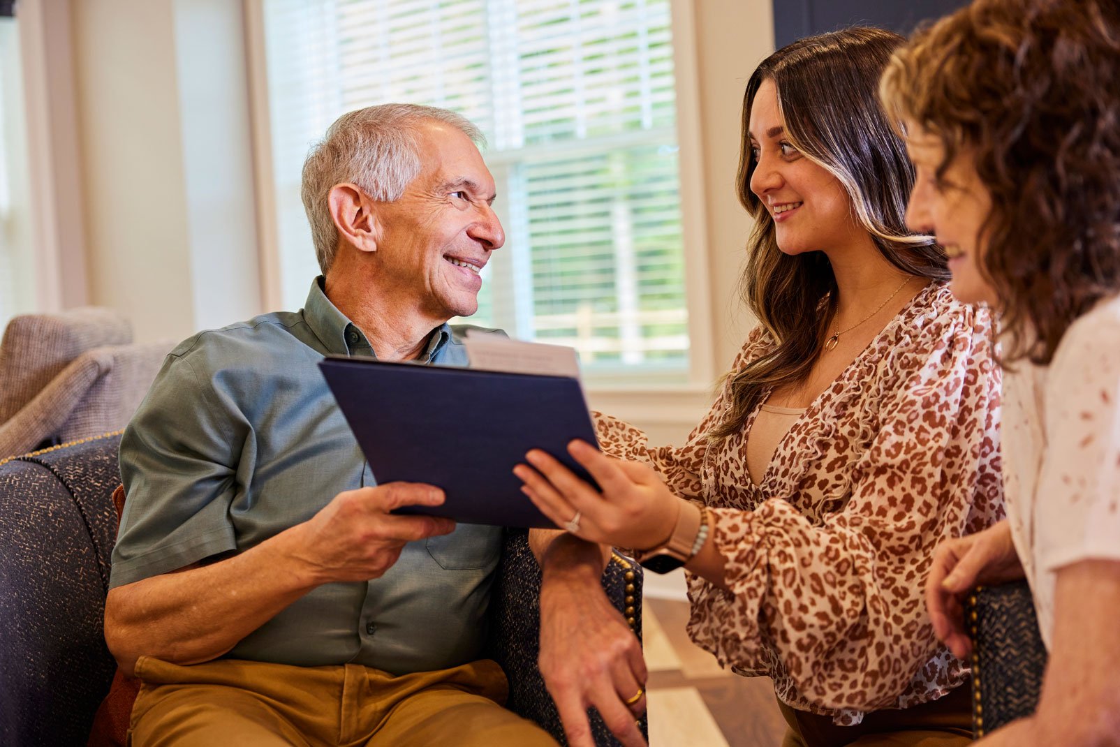 Senior living sales and marketing team member chats with a senior and his family