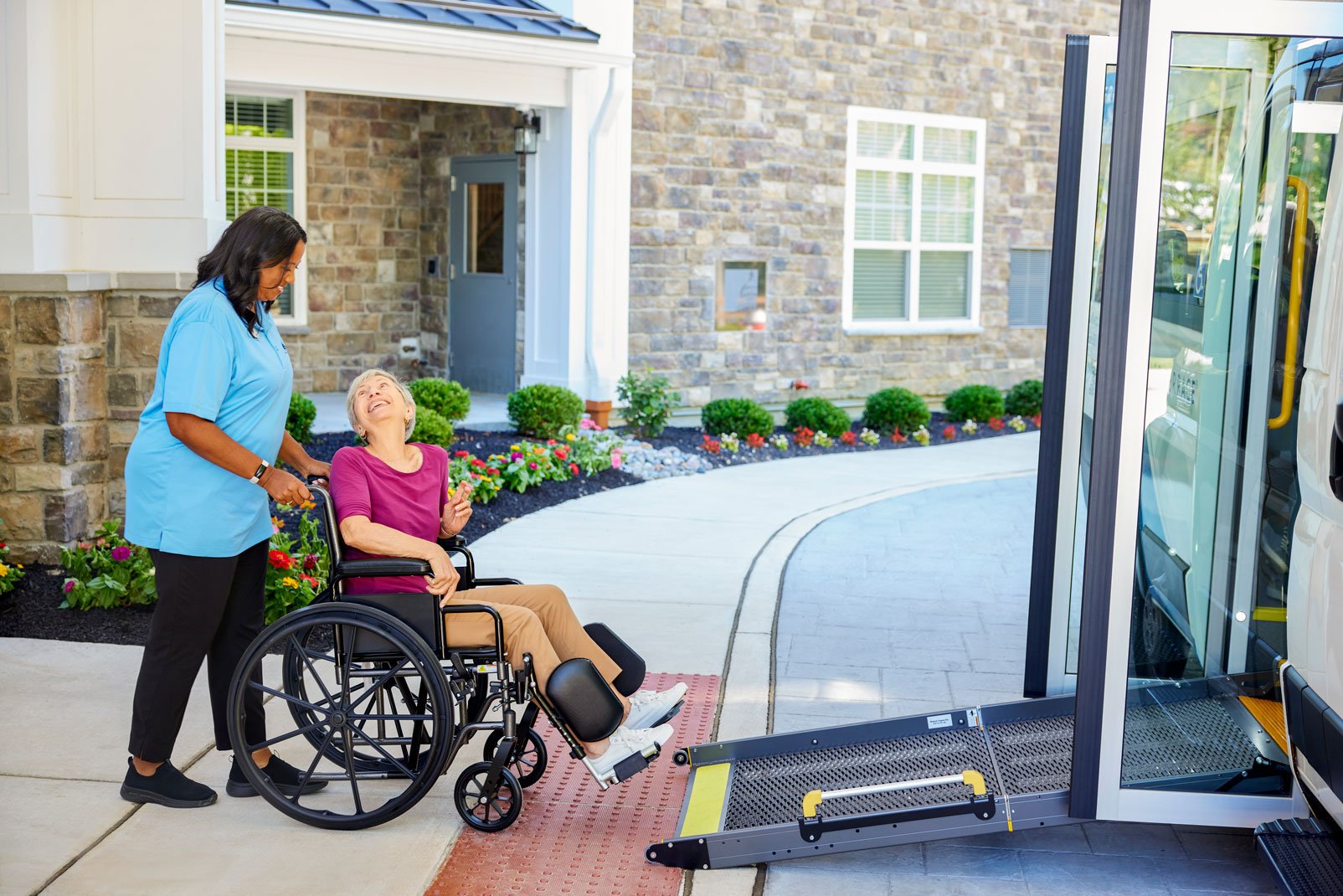 Resident caregiver working in assisted living helps resident in wheelchair