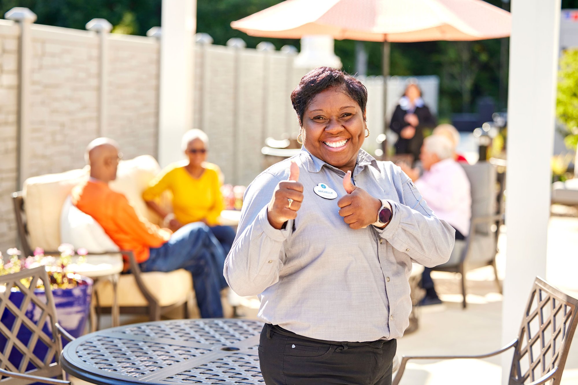 Senior living housekeeper giving a thumbs up after cleaning the outdoor cafe 
