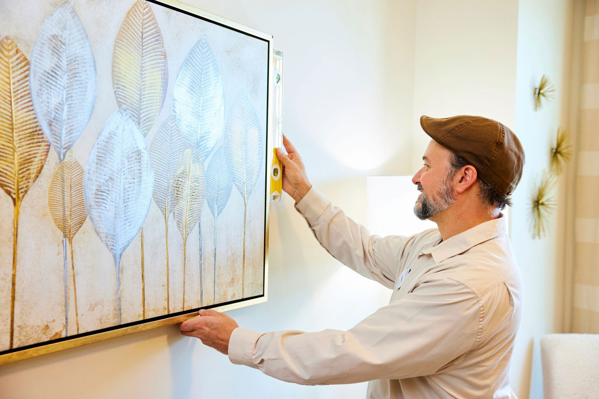 Maintenance team member straightens artwork in a resident apartment