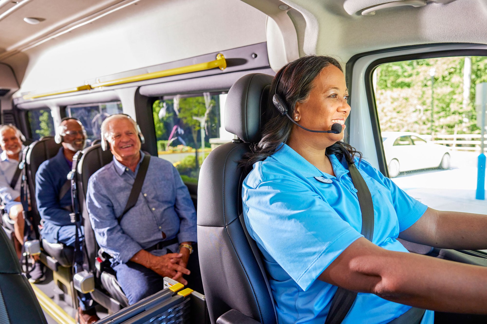 Resident engagement team member driving an Arbor bus with smiling residents in the back