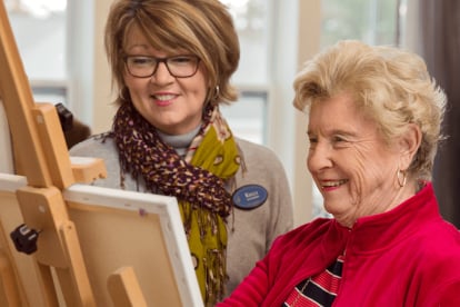 Senior care nurse painting with patient at living facility