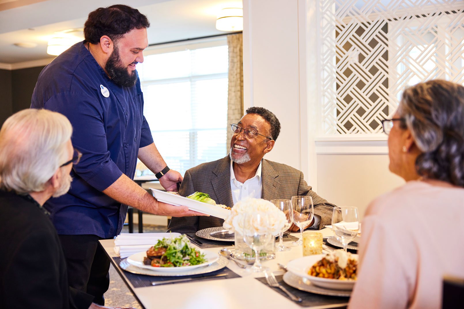 Dining room manager serves beautifully plated entree to a resident