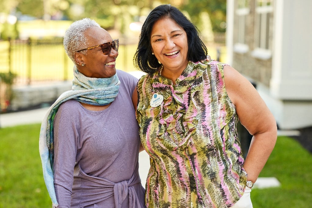 Arbor resident and team member smile and stand in front of a beautifully landscaped community