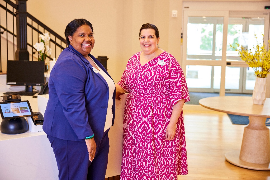 Two smiling team members standing in the lobby of an Arbor community
